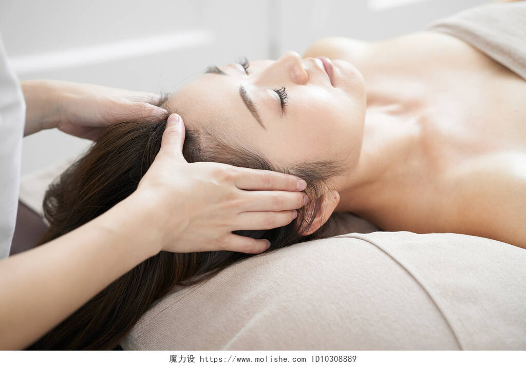 一个女人在一个明亮的美容院接受头部按摩面部按摩中医养生头部按摩